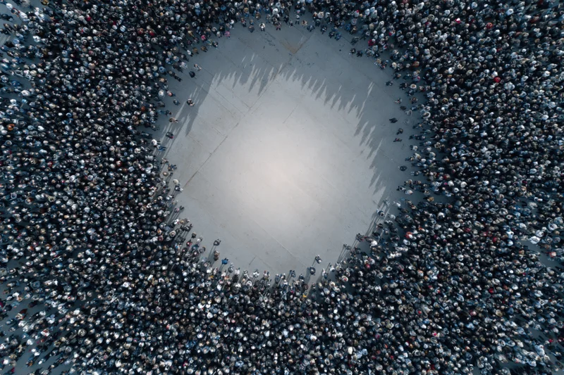 Aerial drone view of a large crowd forming a heart shape on pavement during a public gathering