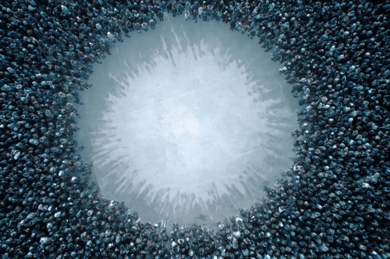 Aerial view of a large crowd forming a circular shape around an open central space