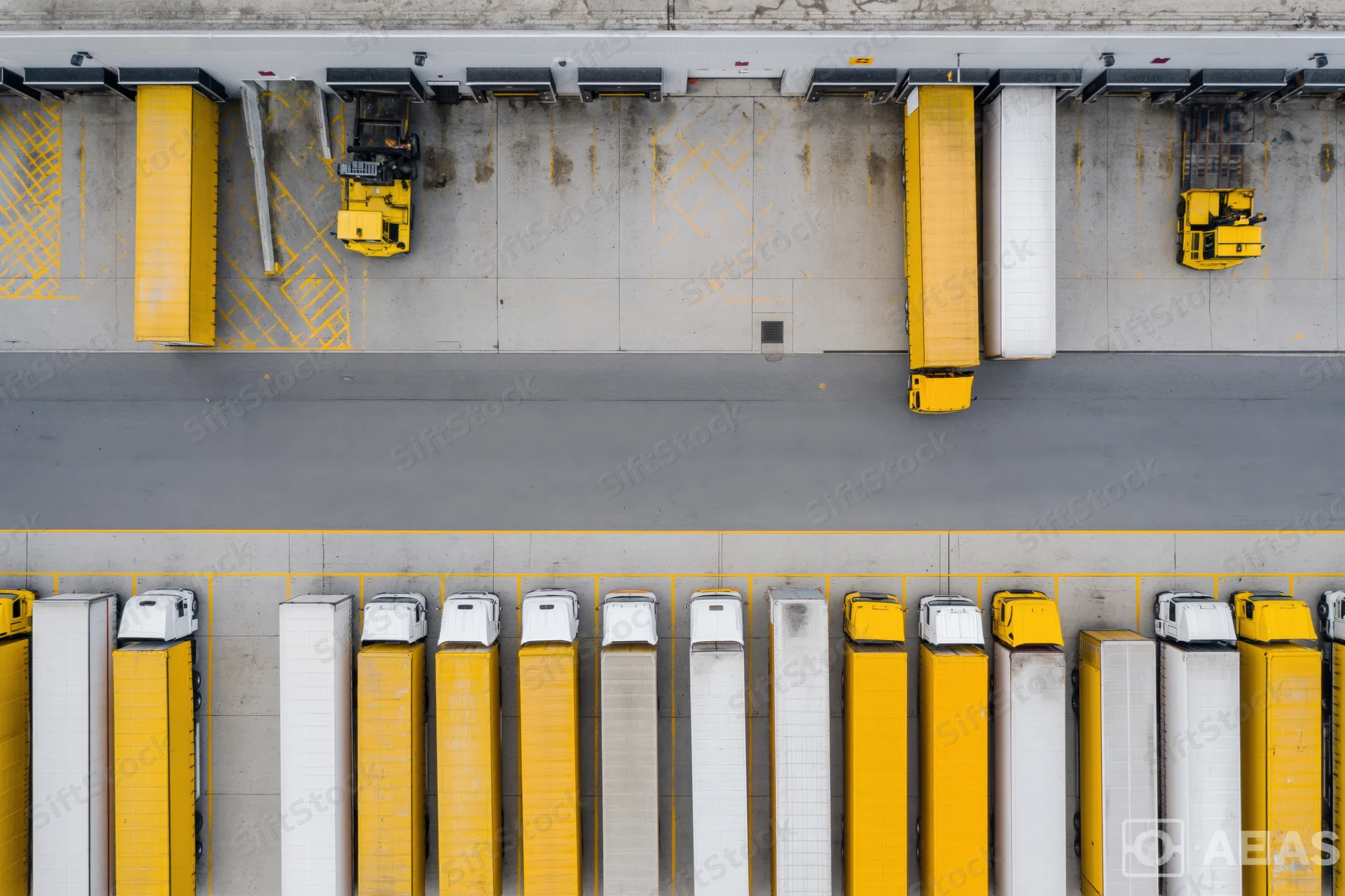 Aerial top-down view of logistics depot with rows of parked trucks at loading docks
