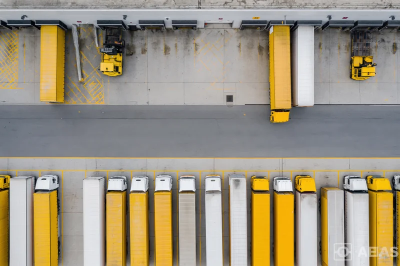 Aerial top-down view of logistics depot with rows of parked trucks at loading docks