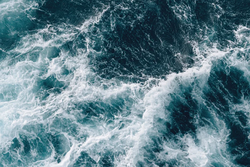 Top-down view of churning deep ocean waves with white foam