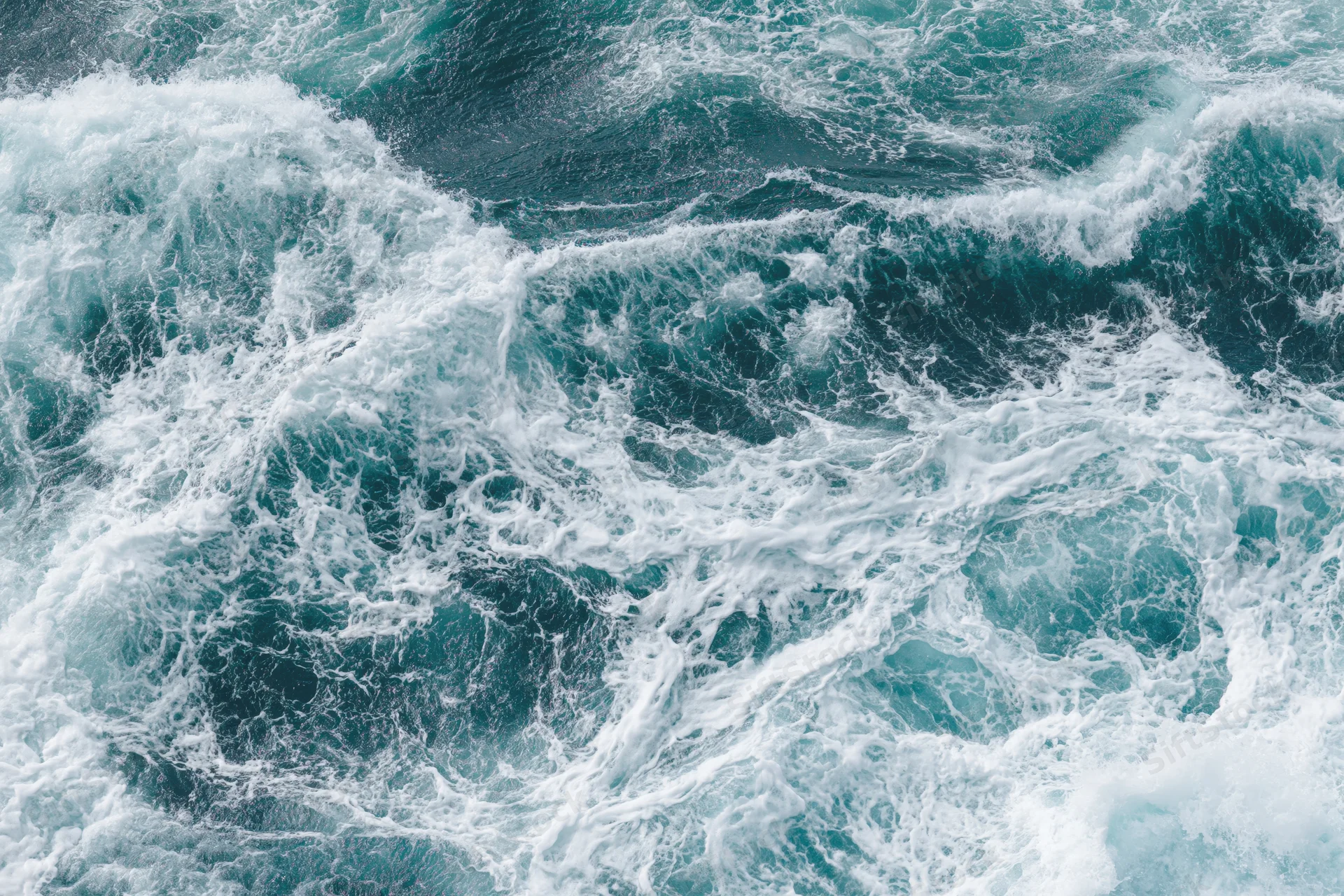 Top-down view of churning ocean waves with white foam on the surface