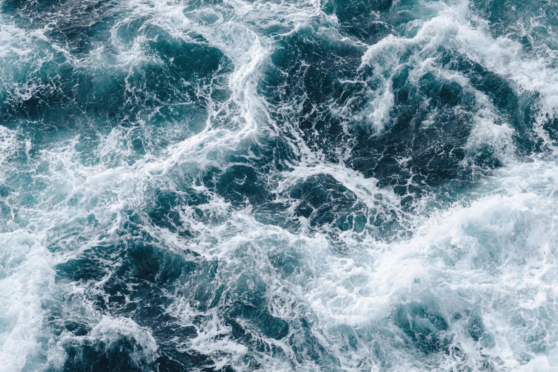 Top-down view of churning deep ocean water with white foam and swirling waves