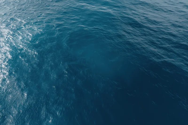 Aerial top-down view of open ocean surface with gentle ripple