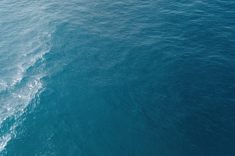 Aerial top-down view of open ocean surface with gentle ripple