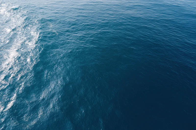 Aerial top-down view of open ocean surface with gentle ripple