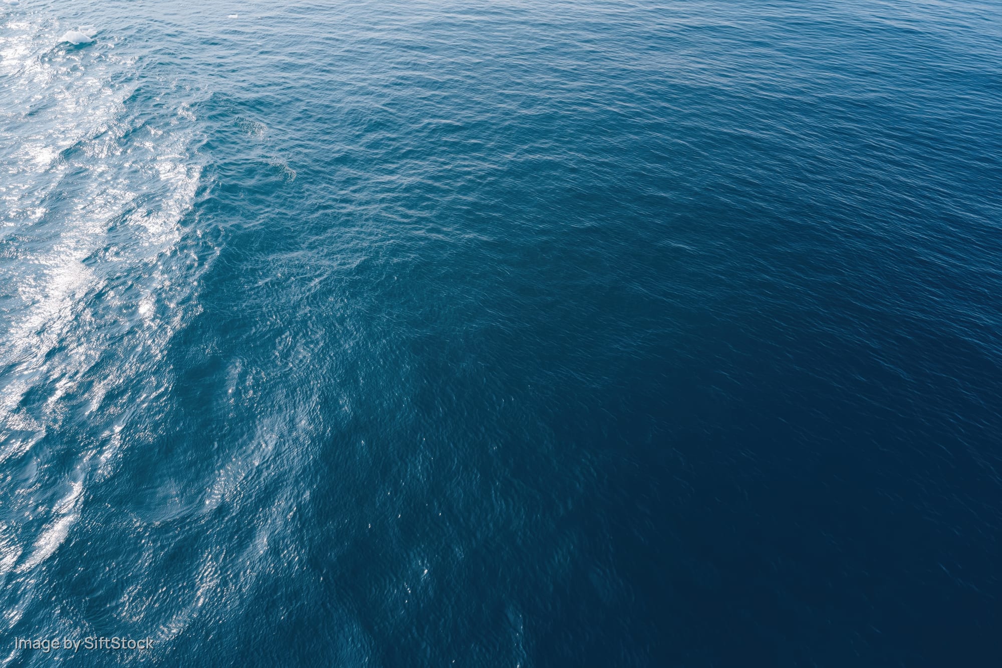 Aerial top-down view of open ocean surface with gentle ripple