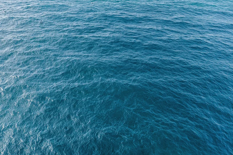 Aerial top-down view of open ocean surface with gentle ripples