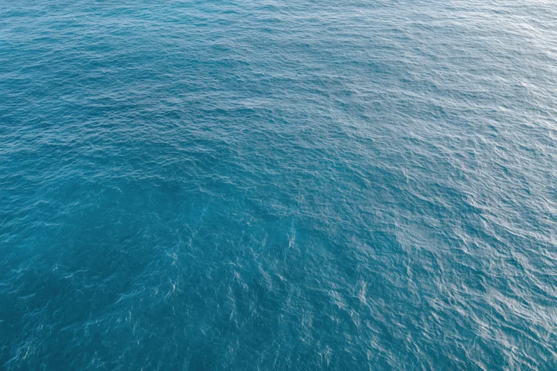 Aerial top-down view of open ocean surface with gentle ripples