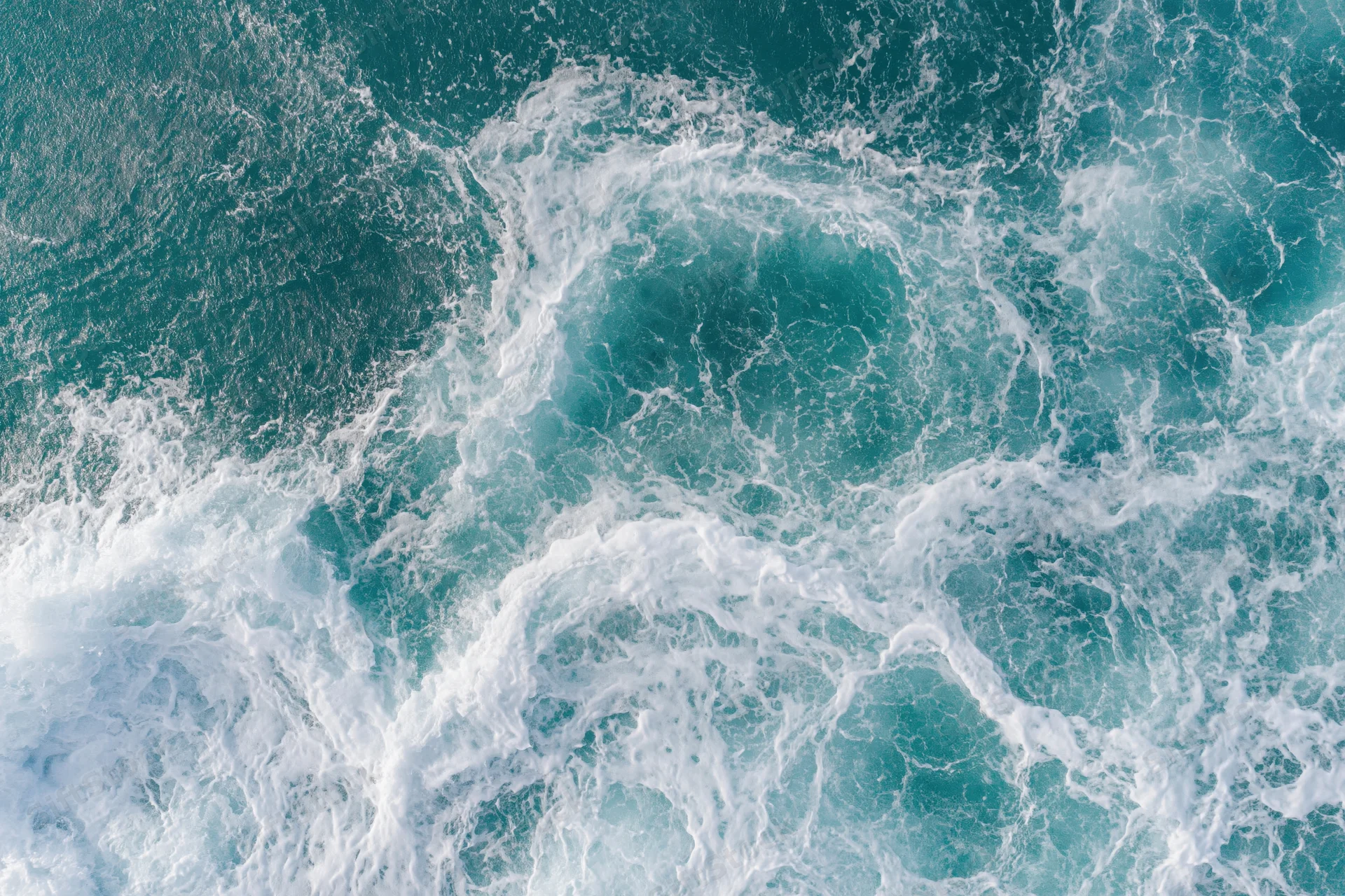 Aerial top-down view of ocean waves with white foam and turquoise water