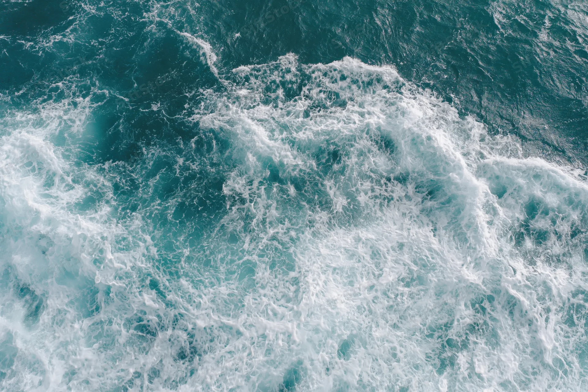 Aerial top-down view of ocean waves with white foam and turquoise water