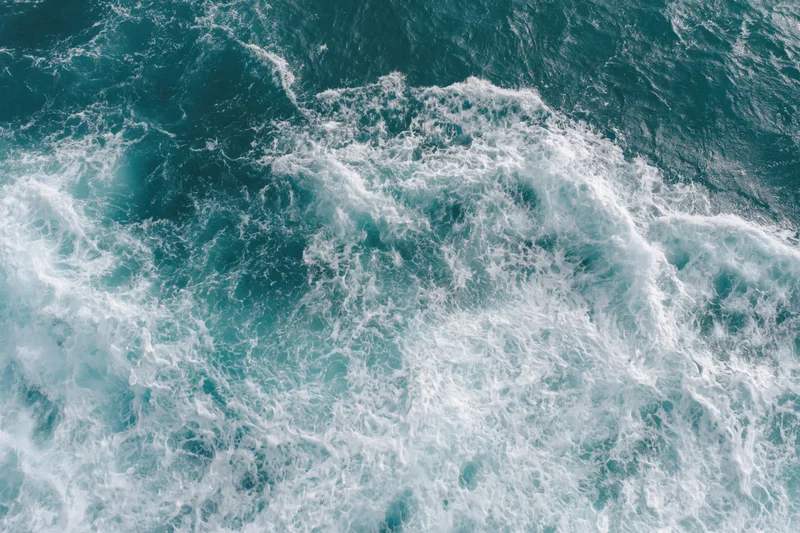 Aerial top-down view of ocean waves with white foam and turquoise water