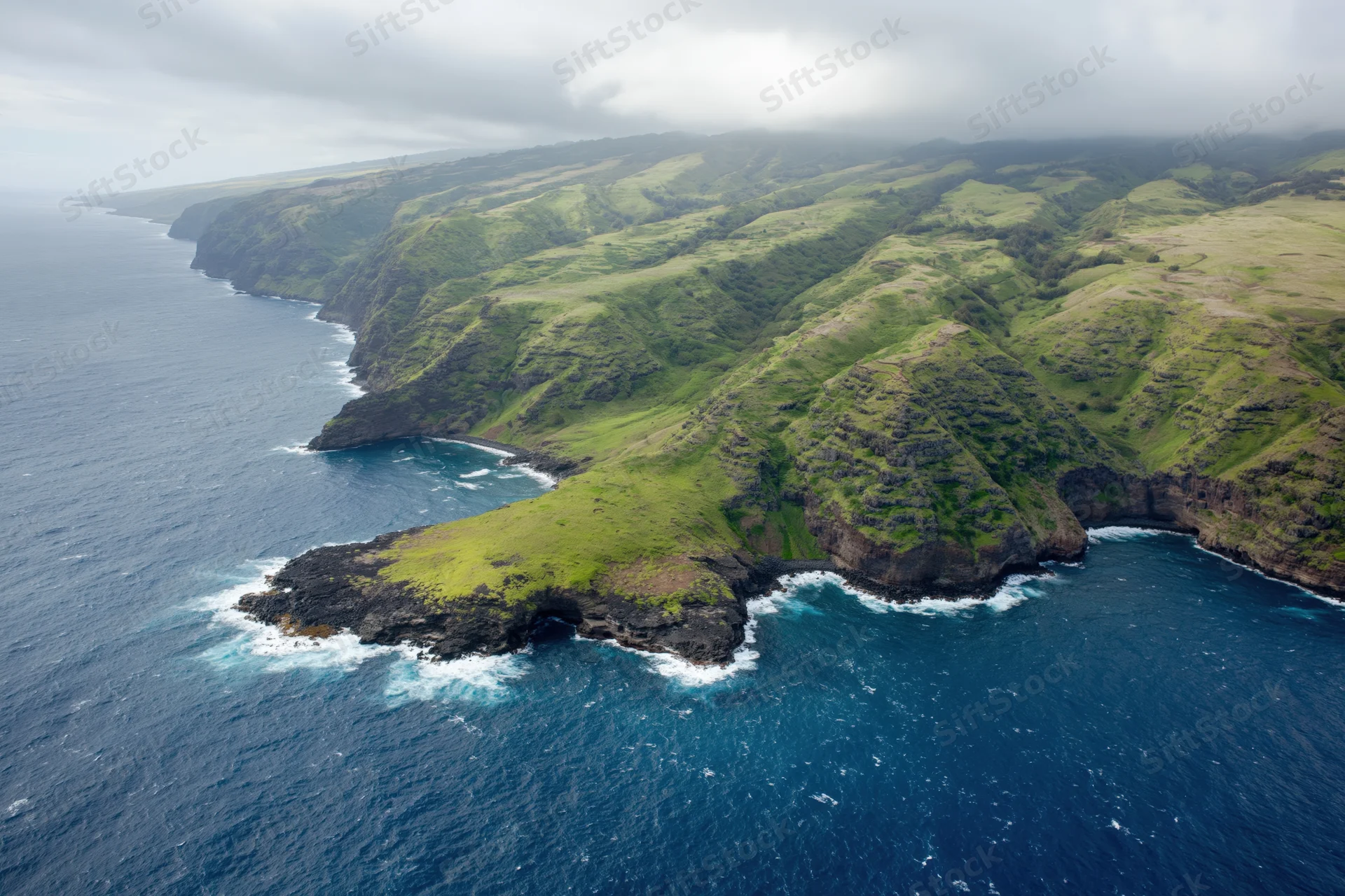 Aerial view of rugged volcanic coastline with green cliffs meeting the ocean