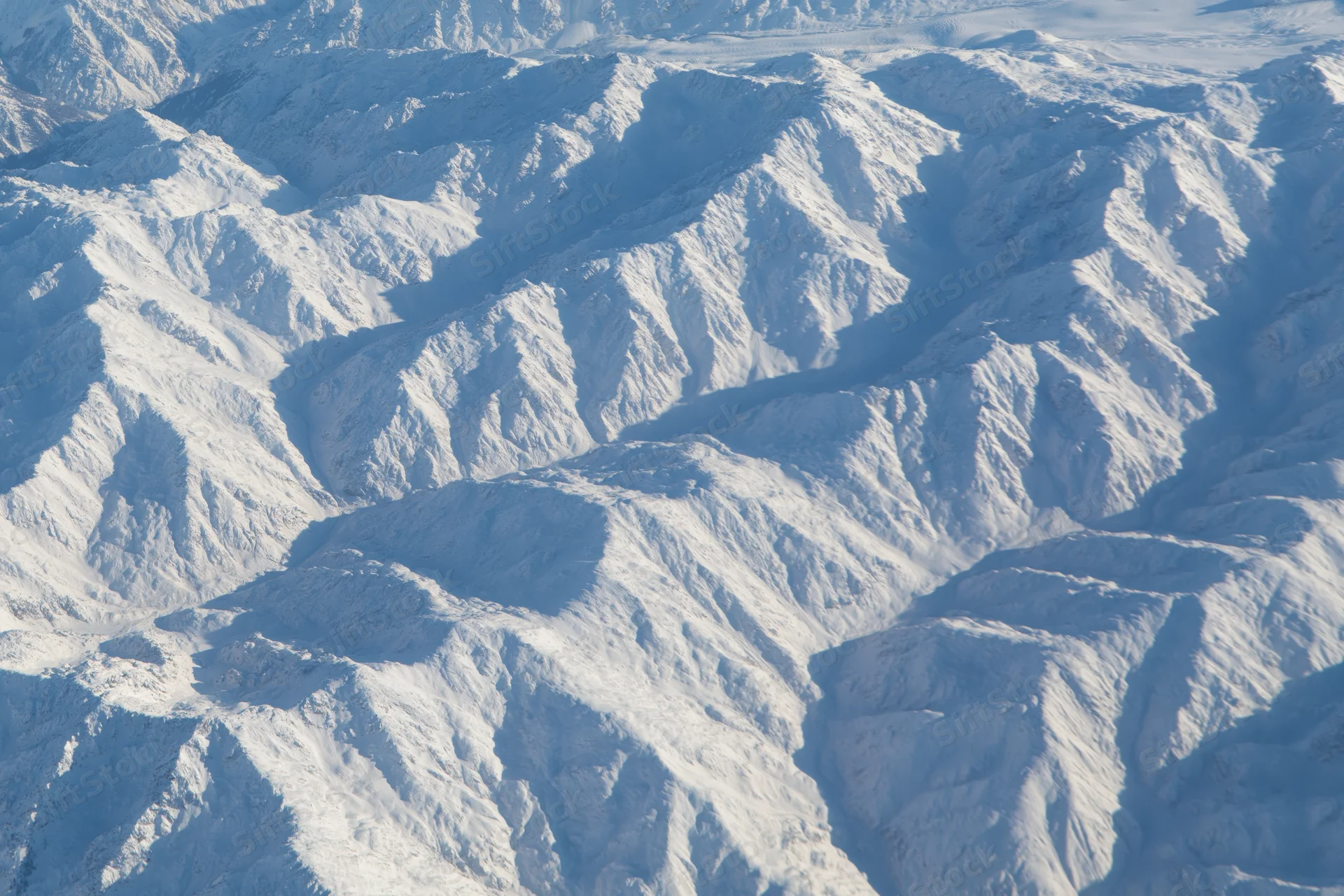 Aerial view of snow-covered mountain ridges and valleys from above