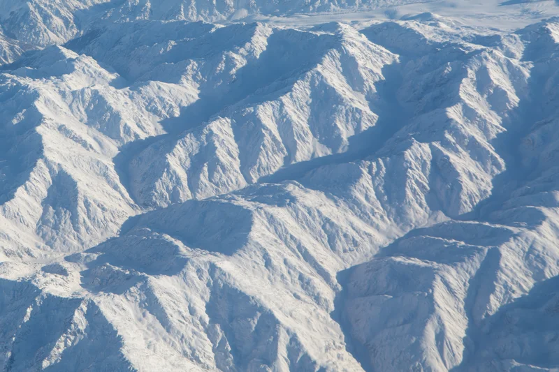 Aerial view of snow-covered mountain ridges and valleys from above