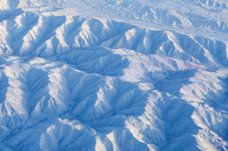 Aerial view of snow-covered mountain ridges and valleys from above