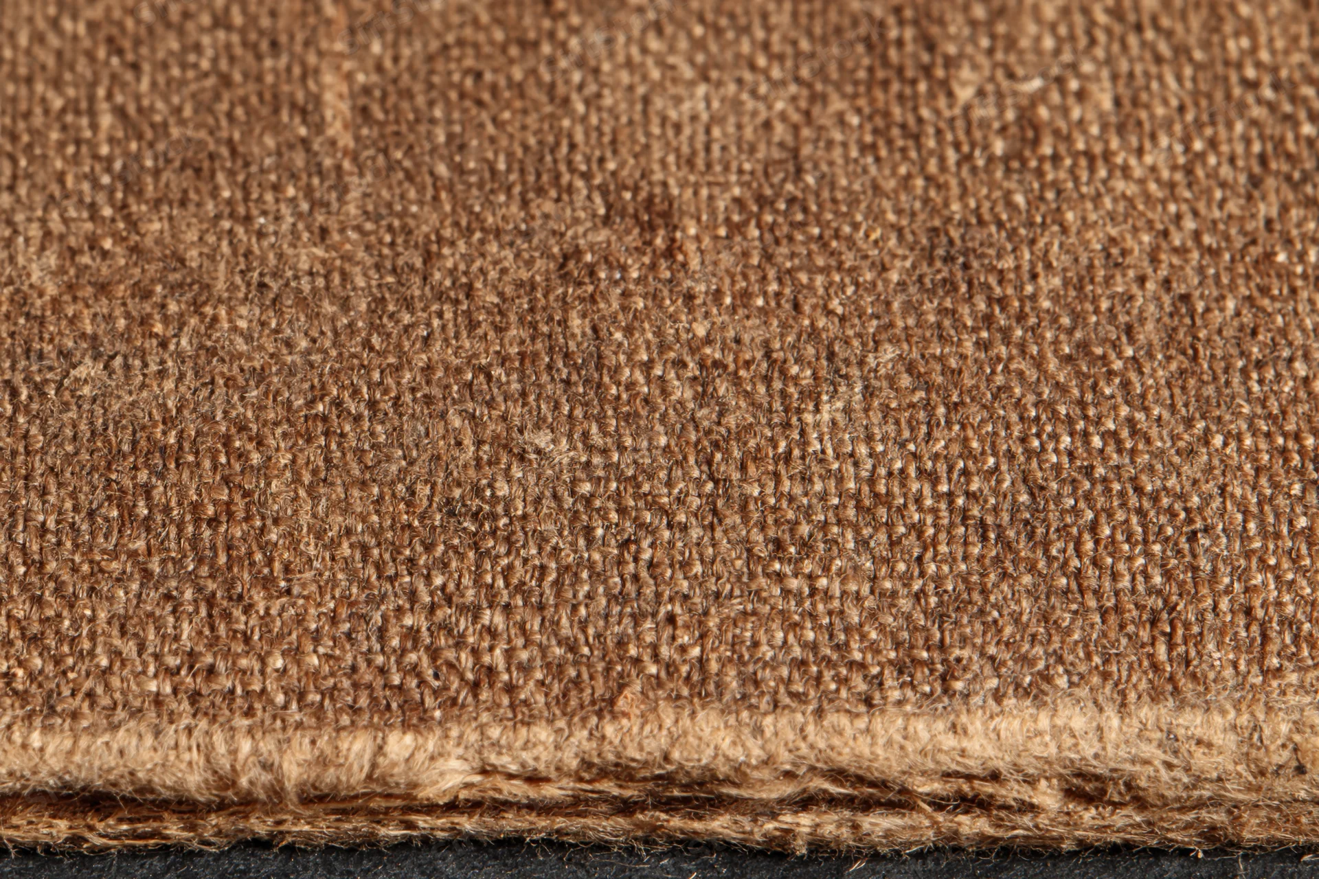 Closeup of worn brown canvas fabric texture with frayed edge