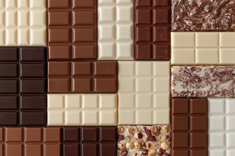 Assorted chocolate bars arranged in a grid pattern viewed from above