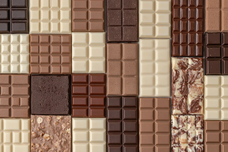 Assorted chocolate bars arranged in a grid pattern viewed from above