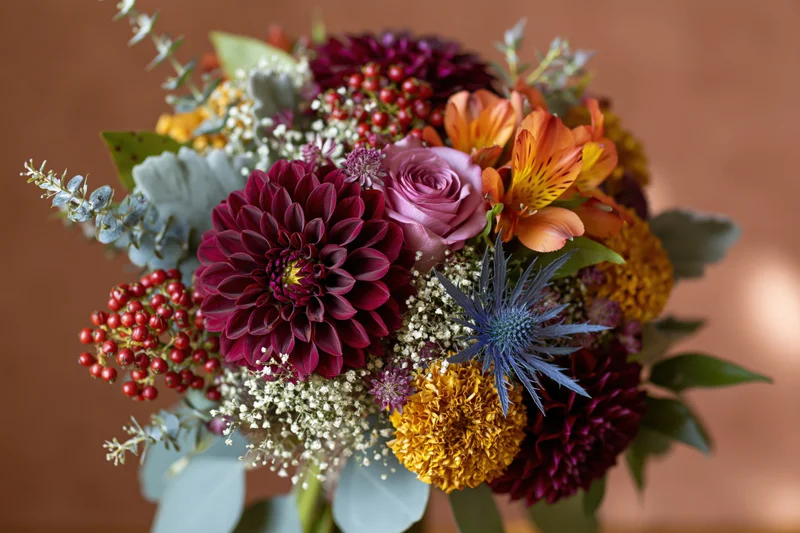 Autumn wedding bouquet with burgundy dahlias, roses, and eucalyptus arranged in a floral display