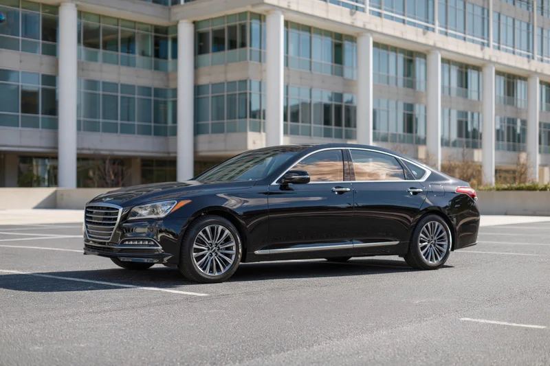 Black executive sedan parked in asphalt lot in front of modern office building