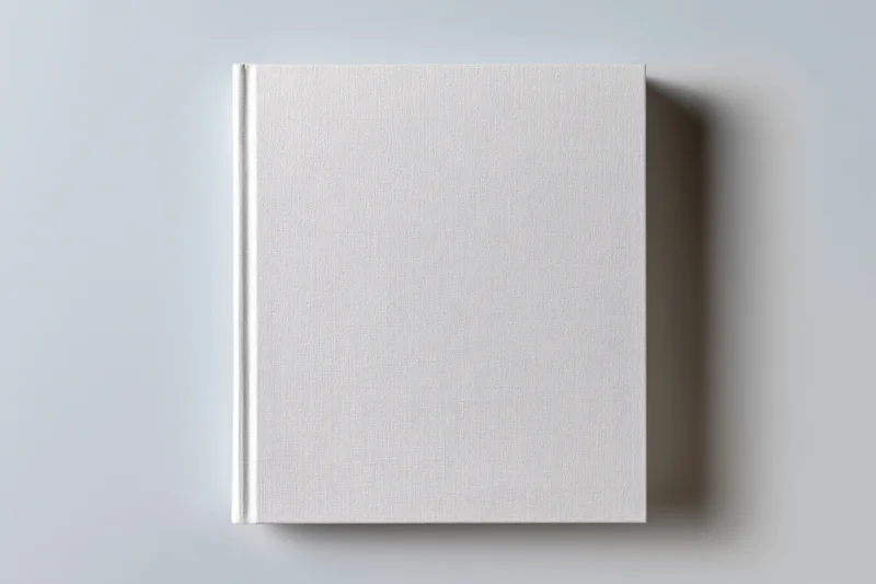 Blank white hardcover book lying flat on light gray surface