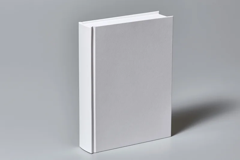 Blank white hardcover book standing upright at slight angle on gray surface
