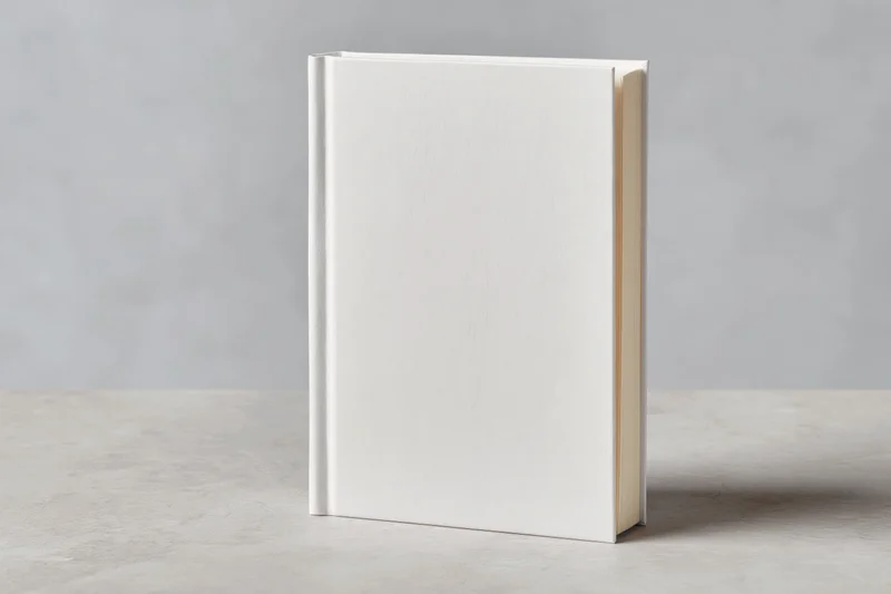 Blank white hardcover book standing upright on a light gray surface