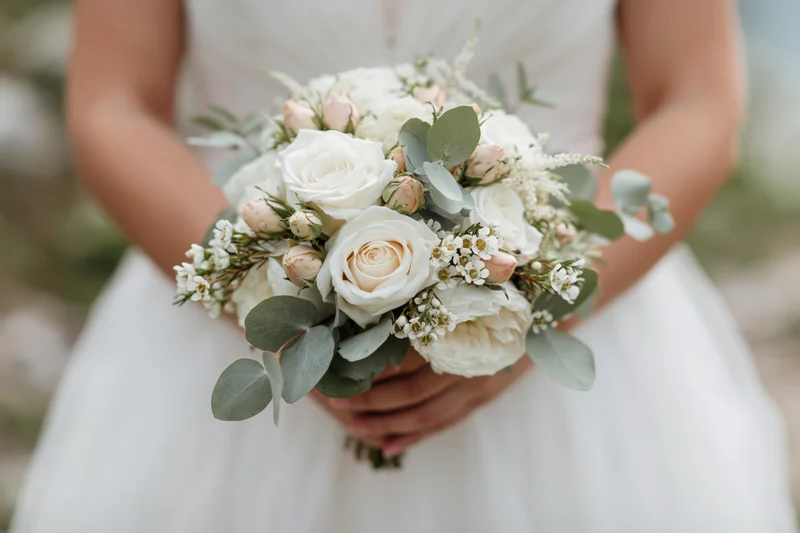 Bride holding a white and green floral bouquet at waist height