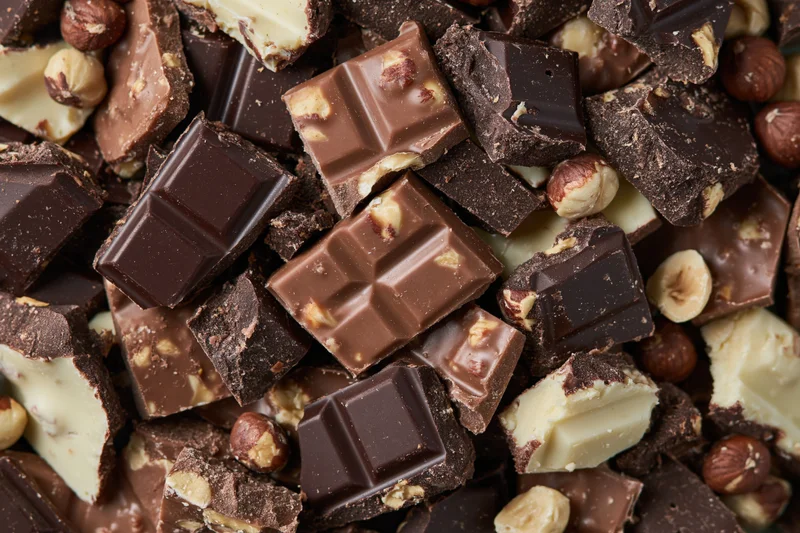 Broken chocolate pieces with hazelnuts piled together in a chaotic heap