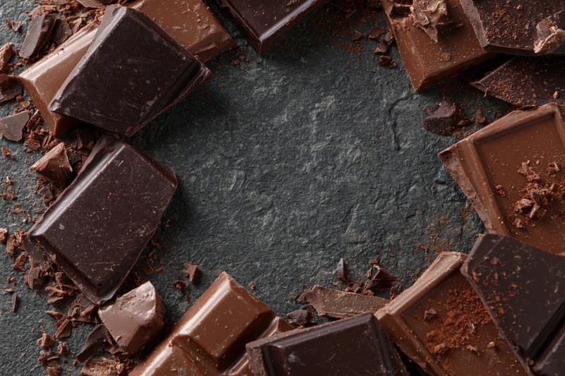Broken dark and milk chocolate pieces arranged loosely around a slate surface