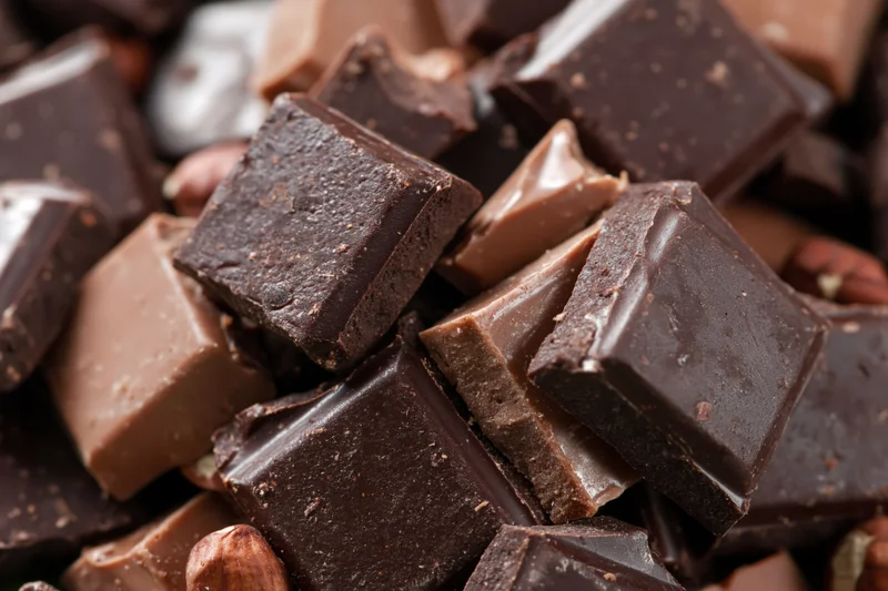 Broken dark and milk chocolate pieces scattered in a pile with nuts