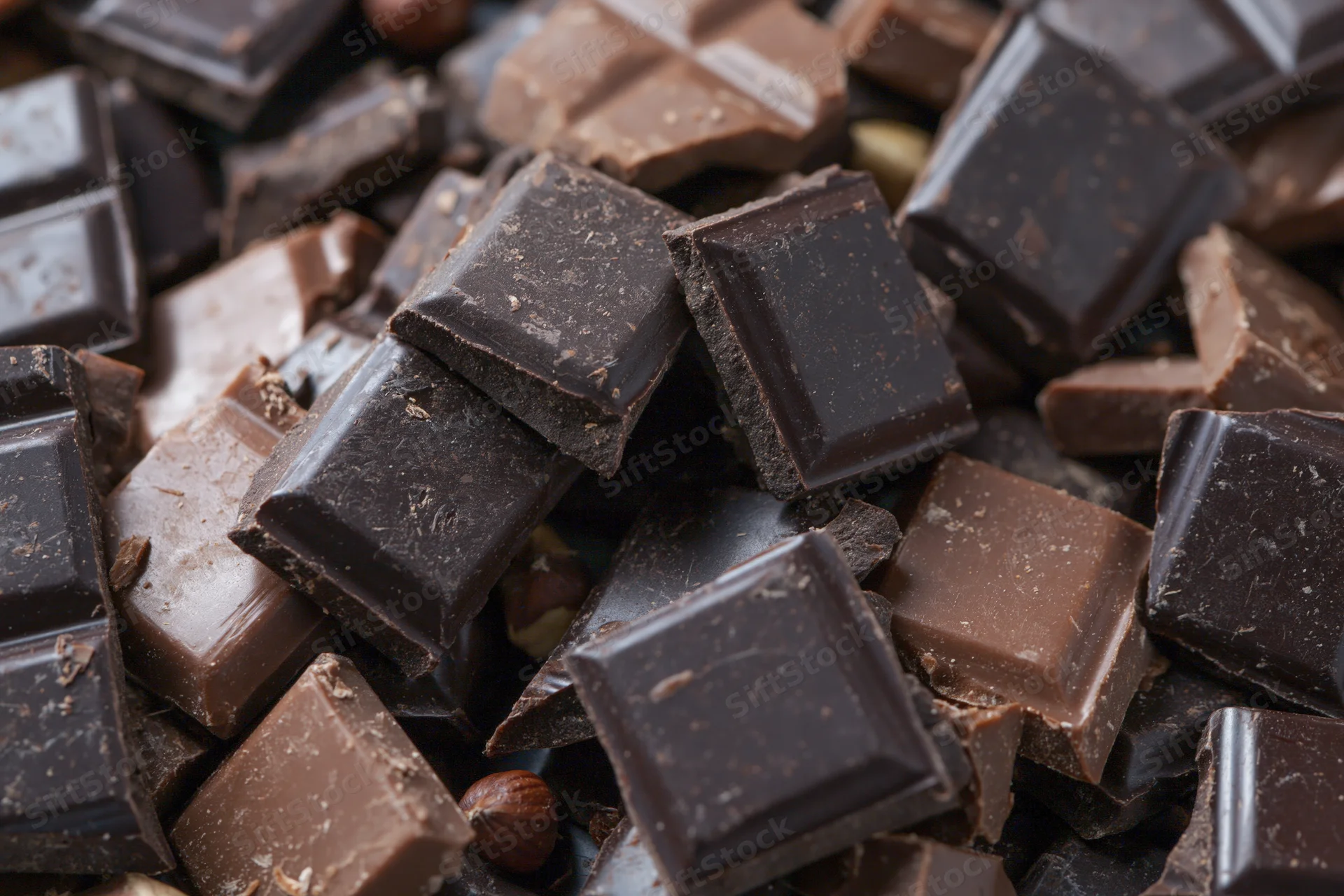 Broken dark and milk chocolate bars scattered in a pile closeup