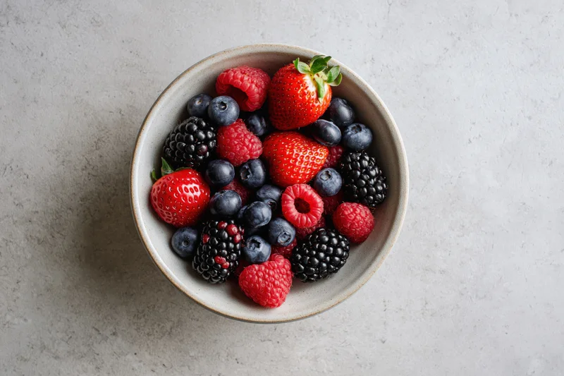 Ceramic bowl filled with mixed berries on a light gray surface