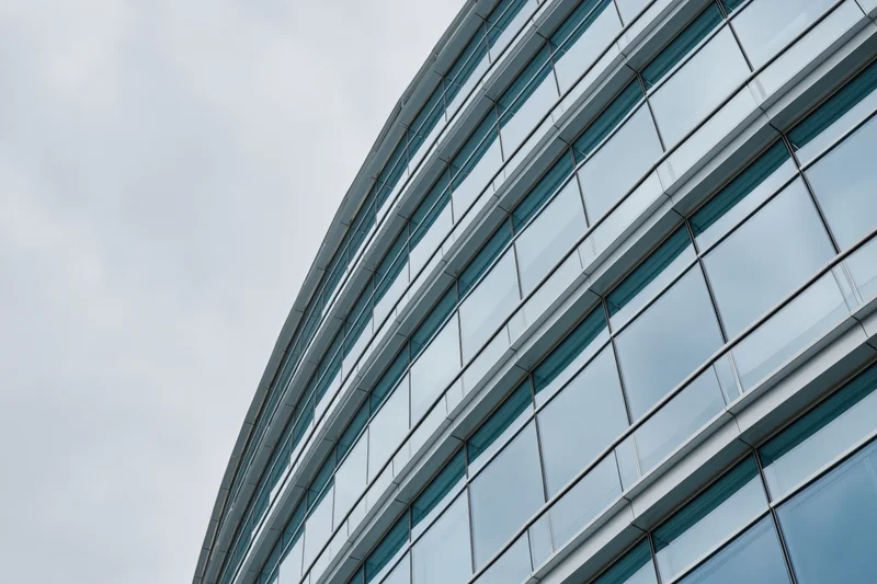 Curved glass curtain wall of modern office building against overcast sky