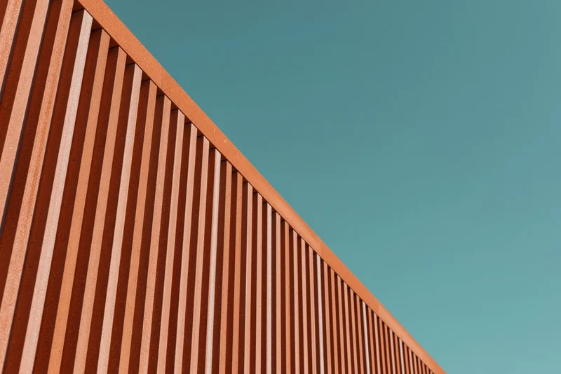 Diagonal view of modern building facade with ribbed cladding against teal sky