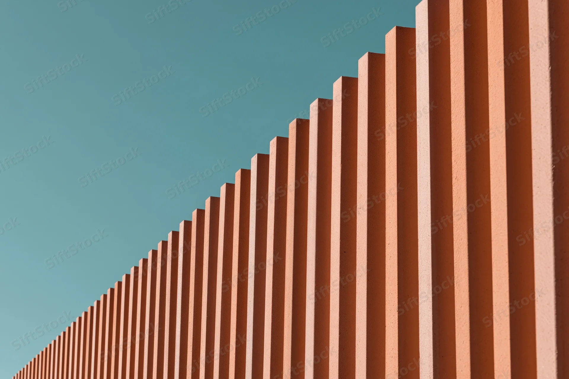 Close-up of modern building exterior cladding with corrugated metal panels against a teal sky