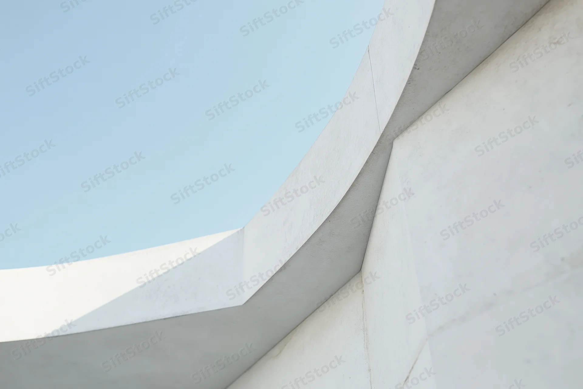 Curved white concrete building exterior against blue sky