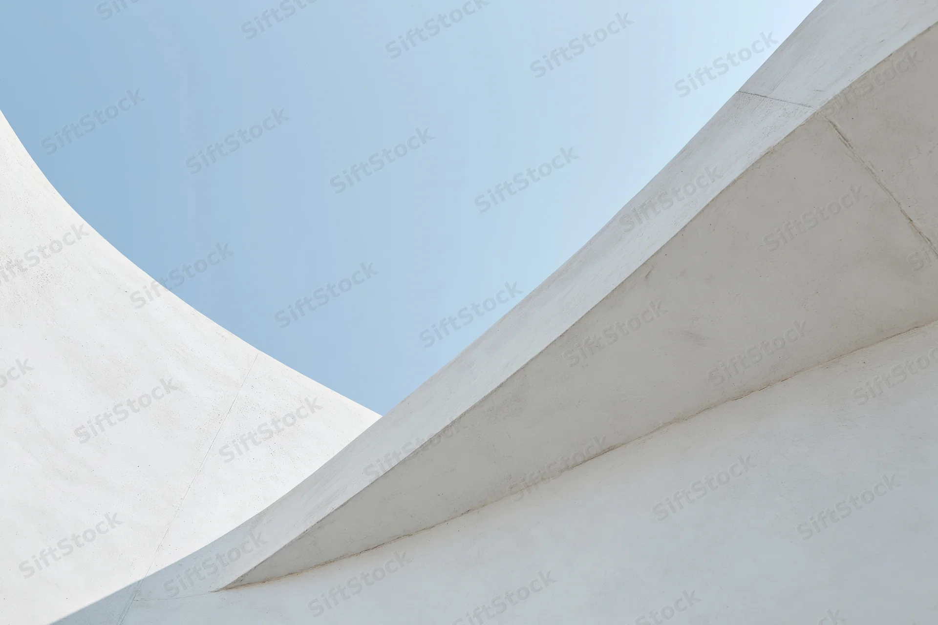Close-up of white concrete building curves and angles against blue sky