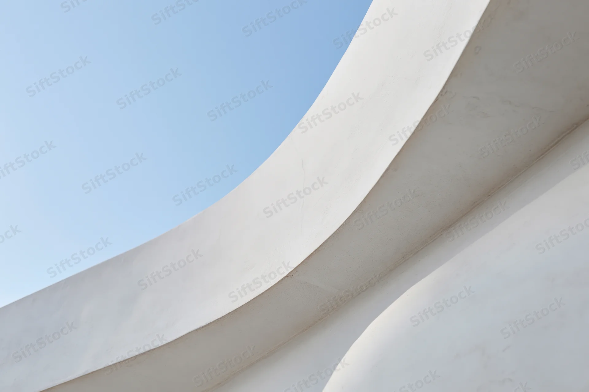 Curved white concrete structure against blue sky