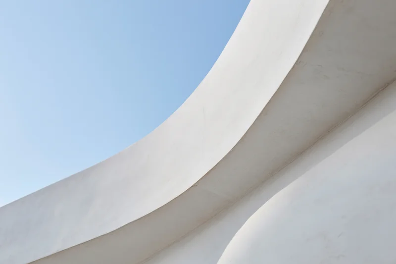 Curved white concrete structure against blue sky
