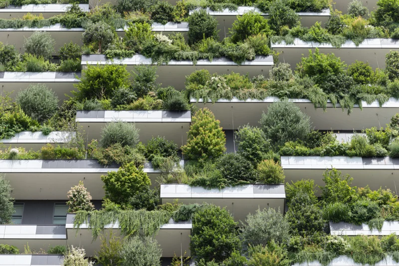 Green plants growing on balconies of a modern residential tower facade