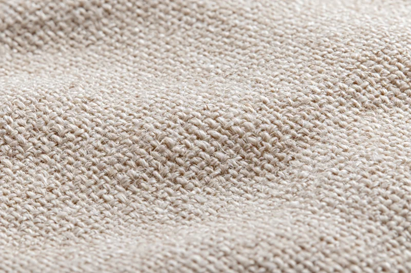 Close-up of natural linen fabric with visible weave pattern filling the frame