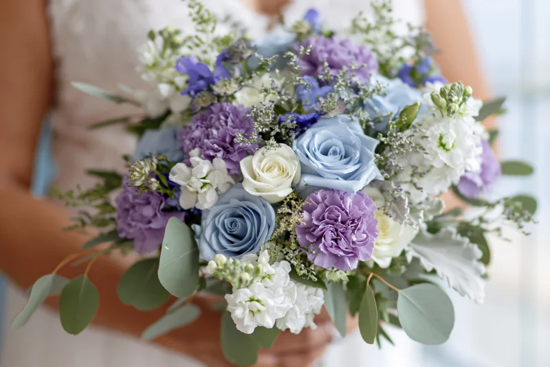 Bride holding a lush bridal bouquet of blue roses, lavender hydrangeas, white flowers and green foliage