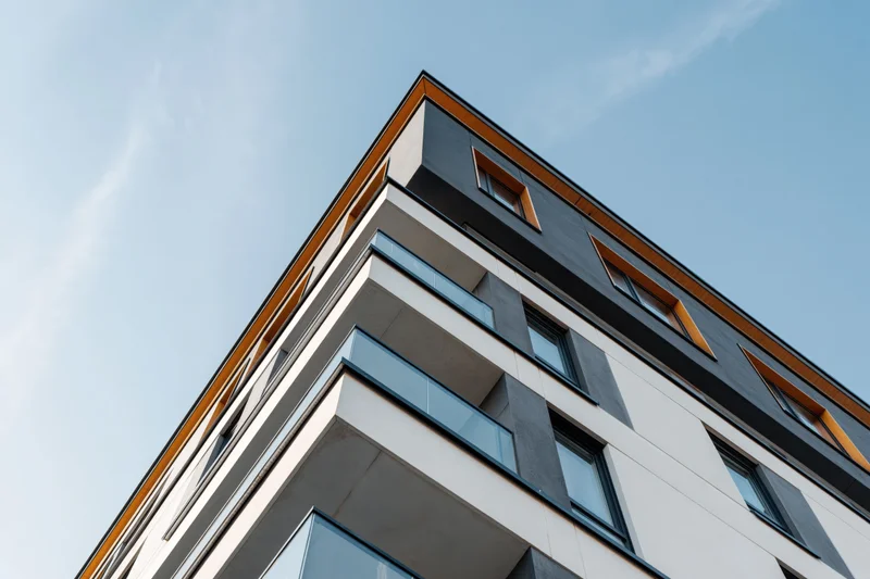 Corner of a modern residential apartment building viewed from below against a clear sky