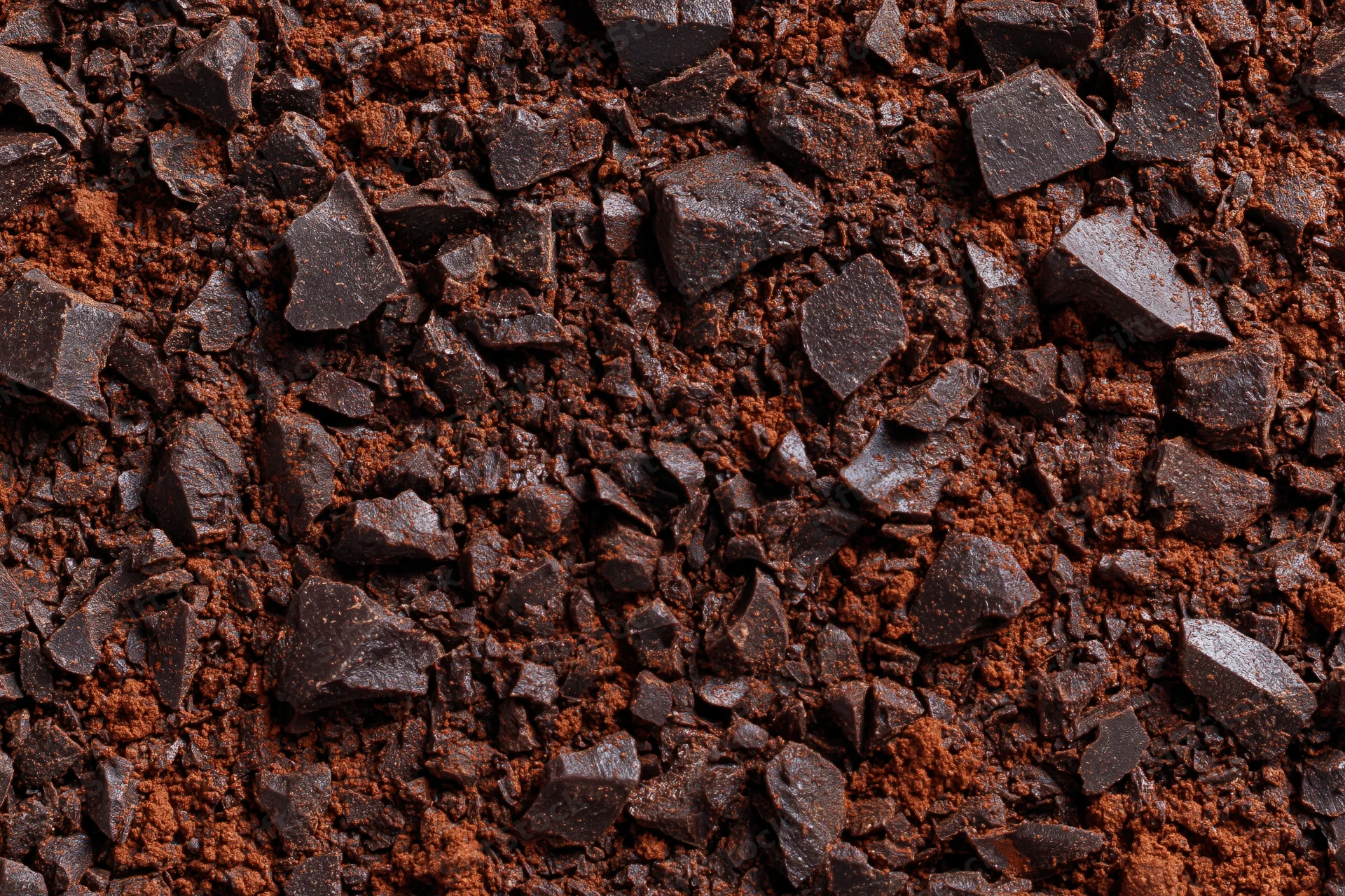 Crushed dark chocolate pieces and cocoa powder scattered across a textured surface