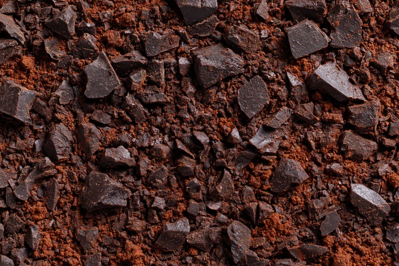 Crushed dark chocolate pieces and cocoa powder scattered across a textured surface