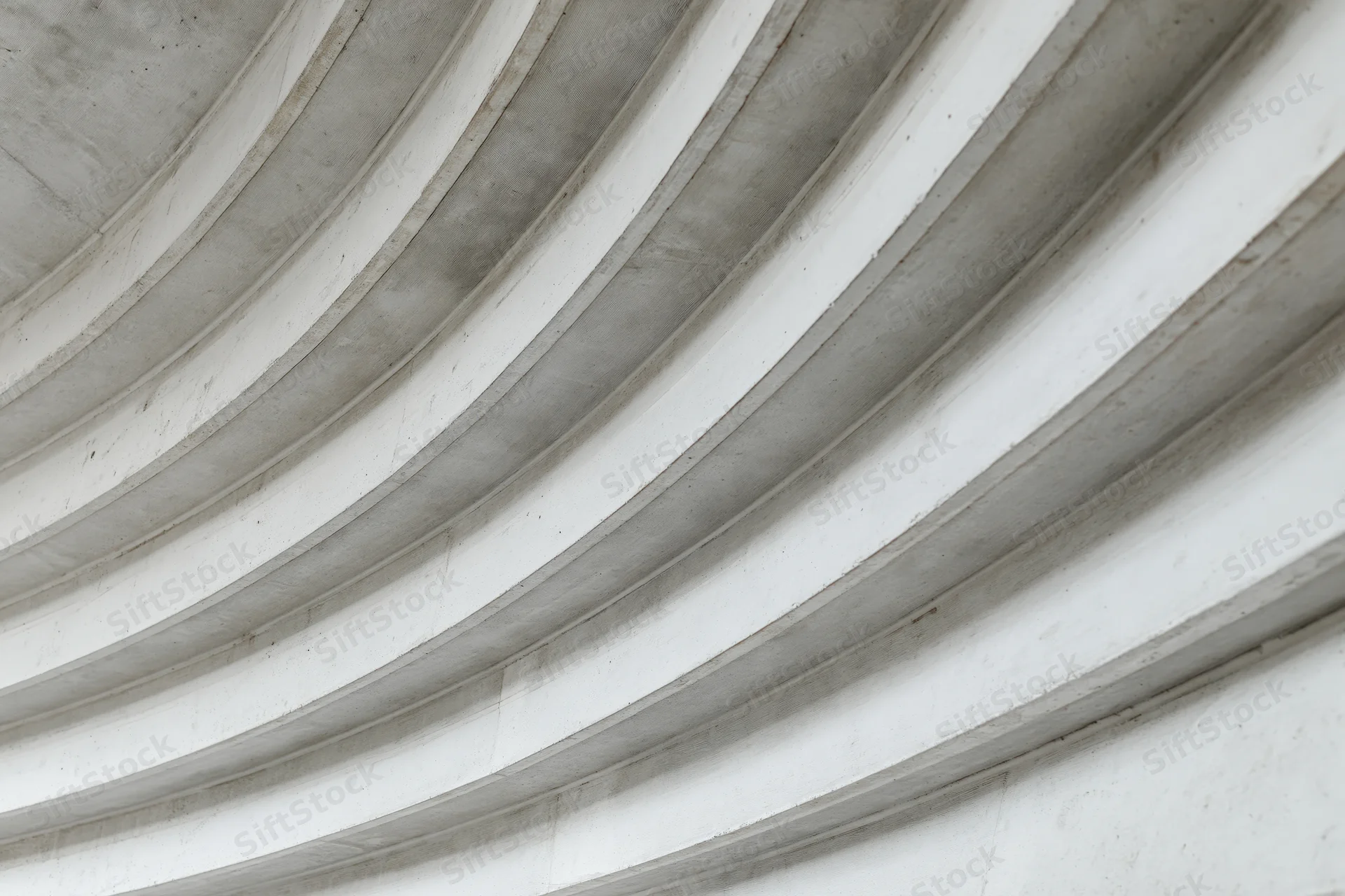 Curved concrete ribs sweeping diagonally across a ceiling interior