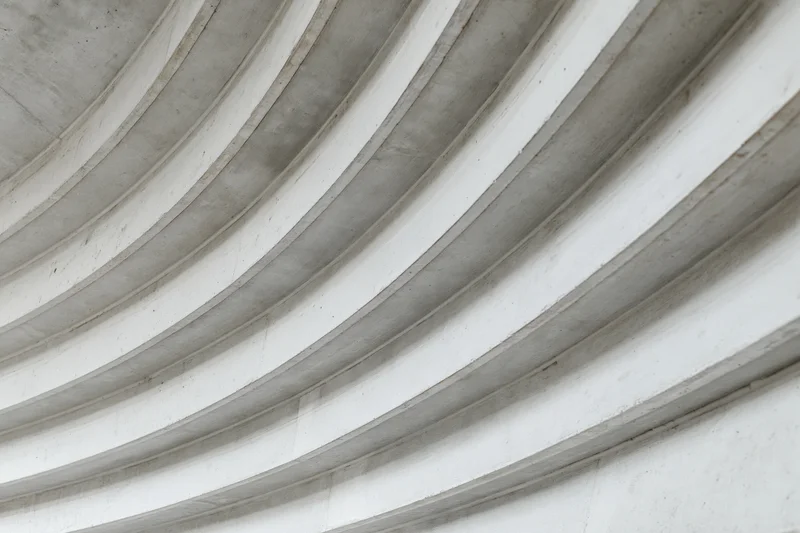 Curved concrete ribs sweeping diagonally across a ceiling interior