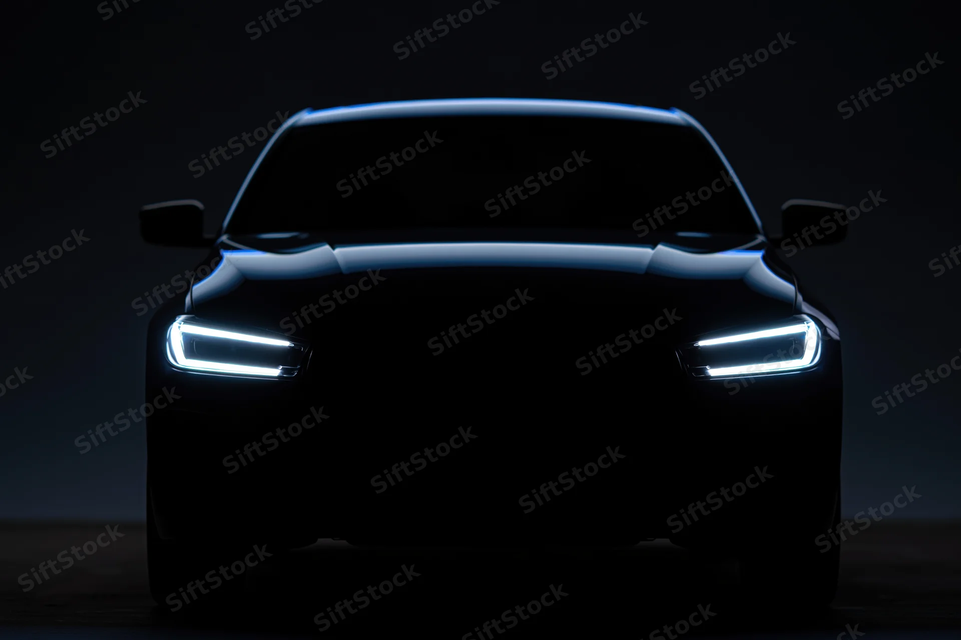 Modern sedan silhouette facing forward with illuminated led headlights in dark setting